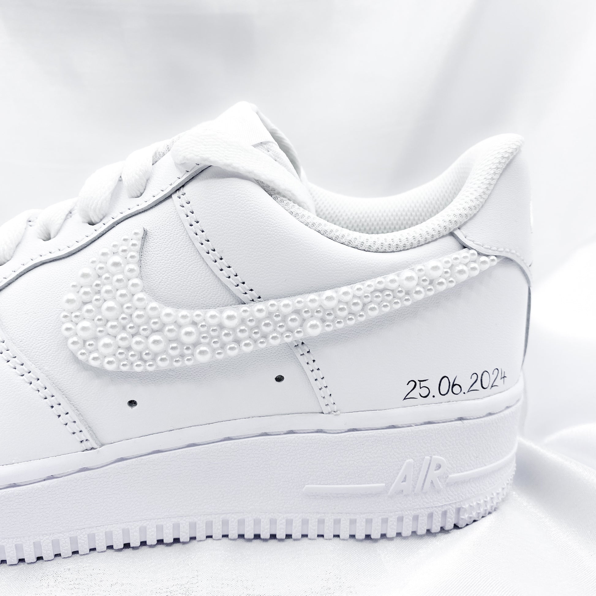 Custom Nike Air Force 1 mit von Hand angebrachten weißen Perlen auf dem Nike Zeichen. Auf dem Schuh steht "25.06.2024"